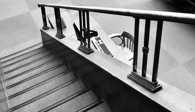 Fotografia czarno biała. W kadrze puste krzesło przy jednym ze stołów w czytelni głównej